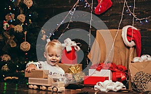 Kid having fun near Christmas tree indoors. Joyful baby looking at camera in christmas at home. Cute little child near