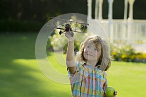 Kid having fun with toy airplane in field. Child pilot aviator with airplane dreams of traveling in summer in nature.