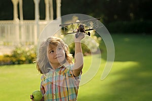 Kid having fun with toy airplane in field. Child pilot aviator with airplane dreams of traveling in summer in nature.