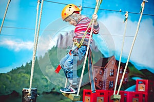 Kid having a good time and having fun at an adventure playground with diferent activities. Happy childhood concept