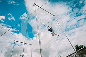 Kid having swing on a high flying trapeze, boy learning acrobatic