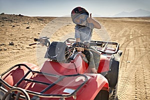 Kid in helmet and protect mask riding quad bike