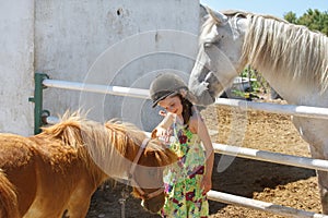 Kid in helmet stroking pony