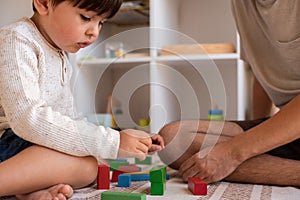 Kid and his father playing at home with wood building blocks. Homeschooling. Stay at home. Family time