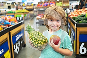 Kid hold pineapple in supermarket. Sale, consumerism and kids concept.
