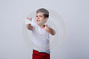 Kid holding discount white card in  hand. Kid with credit card. Little boy showing empty blank paper note copy space.