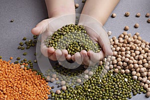 Kid holding mung bean, scattered mash with red lentils and chickpeas, Close up, legumes concept