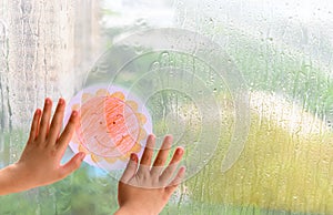 Kid holding picture of smiling sun in a raining day concept of faith and optimism