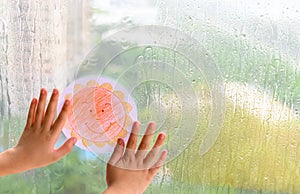 Kid holding picture of smiling sun in a raining day concept of faith and optimism photo