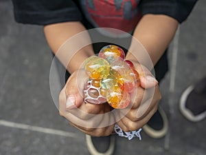 A kid holding and squeezing a colorful stress relief grape balls