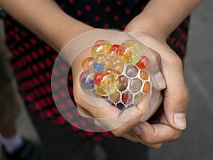 A kid holding and squeezing a colorful stress relief grape balls