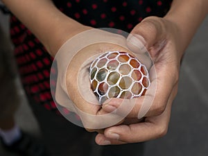 A kid holding and squeezing a colorful stress relief grape balls