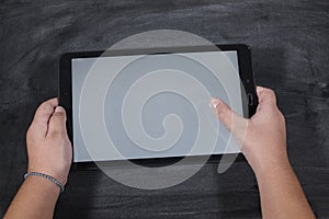 Kid holding a tablet on wooden table. e-learning school