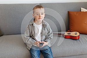 Kid holding TV remote controller. Boy without parental control watching television