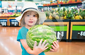 Kid holding watermelon in supermarket. Vegetables in store.