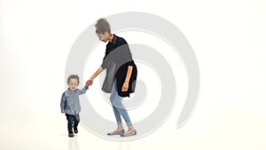 Kid holds his mother`s hand and dances with her. White background. Slow motion