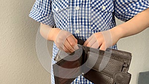 Kid holds a wallet and searches with his fingers, the concept of pocket money, theft, shopping