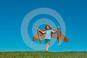 Kid imagination, child pilot with paper wings having fun at outdoor. Summer vacation and travel concept. Boy with toy