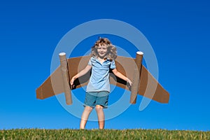 Kid imagination, child pilot with paper wings having fun at outdoor. Summer vacation and travel concept. Boy with toy