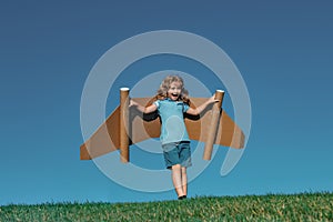Kid imagination, child pilot with paper wings having fun at outdoor. Summer vacation and travel concept. Boy with toy
