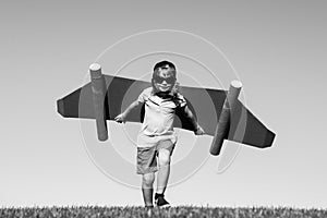 Kid with jet pack superhero. Child pilot against summer sky background. Boy with paper plane flight, toy airplane with