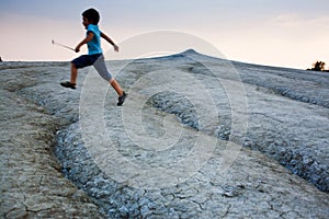 Kid jumping over cracked soil