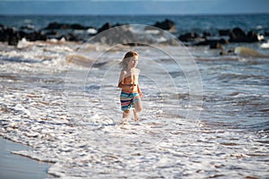 Kid Jumping in Sea Ocean Waves. Jump by Water splashes. Summer day, ocean coast, Beach. Active kids lifestyle and