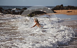 Kid Jumping in Sea Ocean Waves. Jump by Water splashes. Summer day, ocean coast, Beach. Active kids lifestyle and