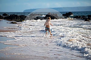 Kid Jumping in Sea Ocean Waves. Jump by Water splashes. Summer day, ocean coast, Beach. Active kids lifestyle and