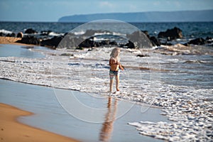 Kid Jumping in Sea Ocean Waves. Jump by Water splashes. Summer day, ocean coast, Beach. Active kids lifestyle and