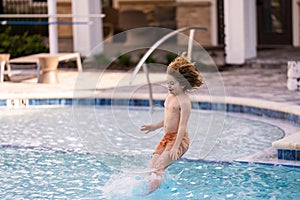 Kid jumping in swim pool. Kid enjoying summer holiday, swiming in pool. Kid having fun on summer holidays at pool. Happy