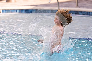Kid jumping in swim pool. Kid splashing in summer water pool. Kid splash in swim pool. Excited happy little boy jumping