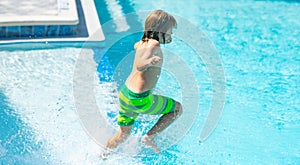 Kid jumping in water pool. Child splashing in summer water pool. Kid splash in pool. Kid jumping in the swimming pool