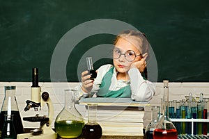 Kid is learning in class on background of blackboard. Biology experiments with microscope. Science and education concept