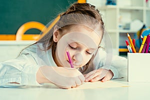 Kid is learning in class on background of blackboard. Preschool education. Home school for pupil.