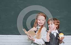 Kid is learning in class on background of blackboard. School kids. Cute little preschool kid boy with Little child girl