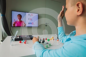 Kid learning remotely. Boy making experiments during online chemistry lesson at home