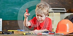 Kid learning to use screwdriver. Concentrated kid working in repairs workshop. Future occupation concept