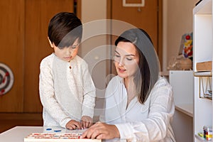 Kid learning to write and read with a alphabet and mother or teacher help. Homeshooling. Learning Community. Montessori School