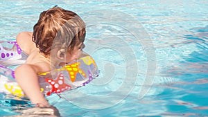 Kid learns to swim using a plastic water ring