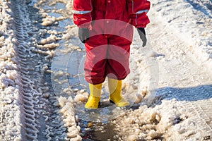 Kid legs in rainboots standing in the ice puddle photo