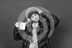 kid listen to music in headphones. morning coffee cup. teen girl in down coat drinking tea.