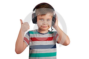Kid listens to his favorite music on headphones and shows thumb up , isolated on white background. Leisure, music and