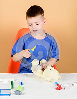 Kid little doctor busy sit table with medical tools. Medicine concept. Medical procedures for teddy bear. Medical