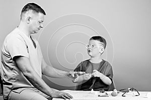 Kid little doctor sit table medical tools. Health care. Medical examination. Boy cute child and his father doctor
