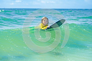 Kid little surfer learn to ride on surfboard on sea waves. Kids outdoor water sport, swimming activity in surf camp. Kid