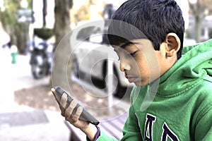 A Kid is looking at his smart phone in a street