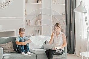 Kid looking how mother working with laptop in living room. Self-education at home.