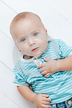 The kid looks beautiful eyes looking mysteriously with his hands on a light background