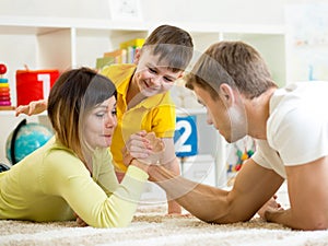 Kid looks at his dad and mom competing in physical strength photo